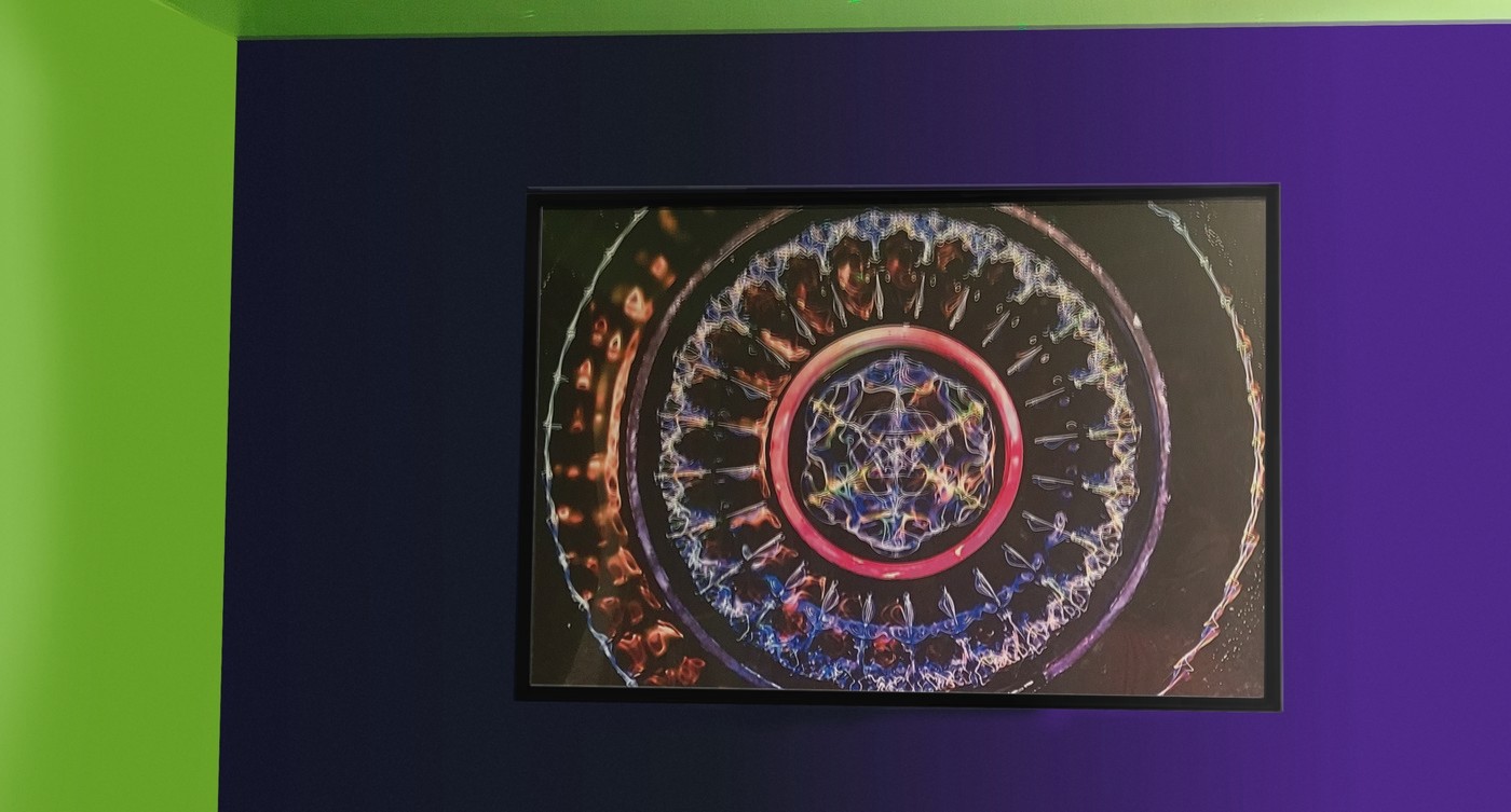 A framed 24 by 36 inch cymatics print hanging on a colorful accent wall